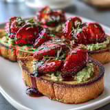 A colorful Galentine's brunch featuring creamy avocado toast topped with fresh strawberries and tangy balsamic glaze.