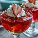 Sparkling strawberry champagne jello shots garnished with fresh berries and edible glitter for a festive Valentine's Day treat.