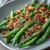 Aromatic sesame garlic green beans with crunchy fried onion topping, perfect alongside grilled meats or tofu.  