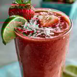 Refreshing vegan smoothie blending frozen strawberries and coconut milk, topped with shredded coconut and fresh strawberry slices for a tropical twist.  