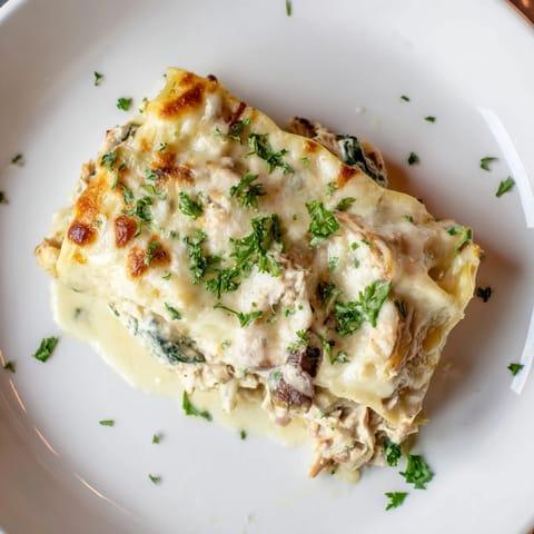 Golden-baked Chicken Alfredo Lasagna ready to serve, garnished with fresh parsley and a side salad.